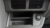 Car console: two USB charging ports and a circular 12V power outlet with a cigarette-lighter symbol nearby a small storage compartment