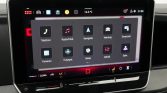 Car touchscreen in a car showing app icons (Phone, Radio, Navigate, Vehicle, SmartLink, Parking, Help/Assist, Setup, Sound, Settings)