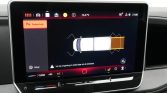 Car infotainment screen showing parking assist with a top-down vehicle graphic and sensor arcs around the front and rear; left panel shows Parking Assist option in Dutch (Parkeerhulp).