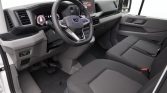 Interior of a modern pickup truck: steering wheel with controls, digital instrument cluster, center touchscreen, and gray cloth seats