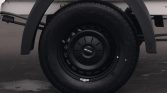 Close-up of a black steel wheel and tire on a white truck, with a centered hubcap.