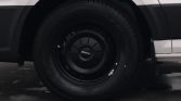 Close-up of a black steel wheel and tire on a white van, hubcap shows the MAN logo in the center
