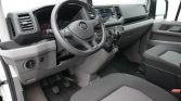 Interior view of a van cockpit: steering wheel with VW logo, dashboard, gear shift, and pedals visible