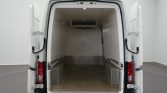 White cargo van with rear doors wide open, showing an empty cargo area with diamond-plate wheel wells and interior light.