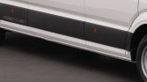 White panel van side with black protective lower trim and small orange side marker lights, showing wheel area.