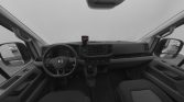 Interior view of a van cockpit showing steering wheel, dashboard, center console, and front seats (monochrome photo).