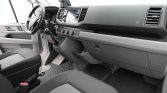 Interior of a van cab showing the steering wheel, dashboard touchscreen, and center controls with a manual gear shifter in view
