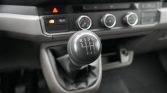 Close-up of a five-speed manual gear lever in a car, showing the shift pattern (R, 1–5) on the knob
