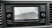 Car infotainment screen showing the rear-view camera with green and red guidance lines for parking, warning text at bottom (Rijweg controleren!).