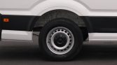 Close-up of a white van's front wheel and lower body, showing a steel rim and black trim.