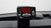 Dashboard-mounted handheld device with a red numeric display and labeled buttons (SET, +, −) on a car dash.