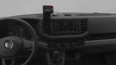 Interior of a Volkswagen driver’s cabin with steering wheel, center touchscreen, manual gear shifter, and a device mounted on the dash