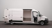White cargo van with the side door open, revealing an empty aluminum cargo area and the driver’s seat visible inside.