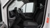 Front interior of a white van with the driver’s seat, steering wheel, and passenger seat visible.