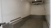 Empty white cargo trailer interior with diamond-plate metal flooring and an overhead cooling unit at the front end.