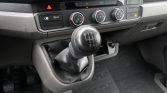 Manual gear shift in a car with R-1-3-5 on top and 2-4-6 beneath, plus climate control dials and hazard button on the dashboard.