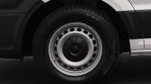 Close-up of a car's steel wheel with white hubcap and black tire on a dark road surface