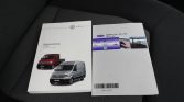 Two Volkswagen vehicle manuals on a car seat, showing red and silver Crafter vans on the left booklet.