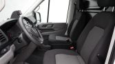 Front cabin of a white van with black and gray driver and passenger seats, steering wheel, and dashboard visible, empty and ready to drive in daylight.
