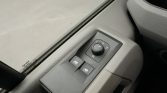 Car interior door panel with power window switches and a circular side‑mirror adjustment knob (L/R).