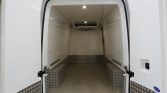 Empty white cargo van interior with open rear doors, diamond-plate side benches, and a ceiling air conditioner in front.