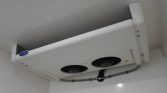 Ceiling-mounted Carrier refrigeration unit with two circular fans and accompanying conduit.