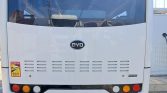 White bus seen from the rear with BYD logo, taillights, and a warning sticker on the lower left corner of the back panel.