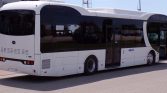 White low-floor transit bus photographed from the side with doors open, parked on a paved area.