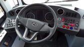 Bus driver's cockpit with steering wheel, instrument gauges, and a panel of switches and gear buttons (D, N, R).