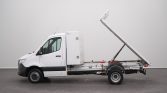 White utility truck with a tilted flatbed in a spacious studio setting, ready for loading/unloading.
