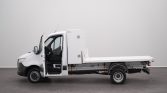 Side view of a white flatbed tow truck with the driver's door open, parked in a studio setting.