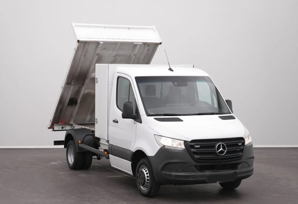 White Mercedes-Benz utility dump truck with its bed raised, ready to unload.