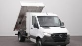 White Mercedes-Benz utility dump truck with its bed raised, ready to unload.