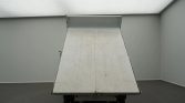 Rear view of a white dump truck bed raised at a slight angle in an empty room-based environment.