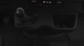 Manual gear shift with leather boot in a dark car interior, center console and small storage bin nearby.