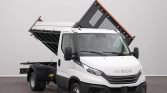 White Iveco dump truck with its bed raised for unloading, indoors in a neutral setting.