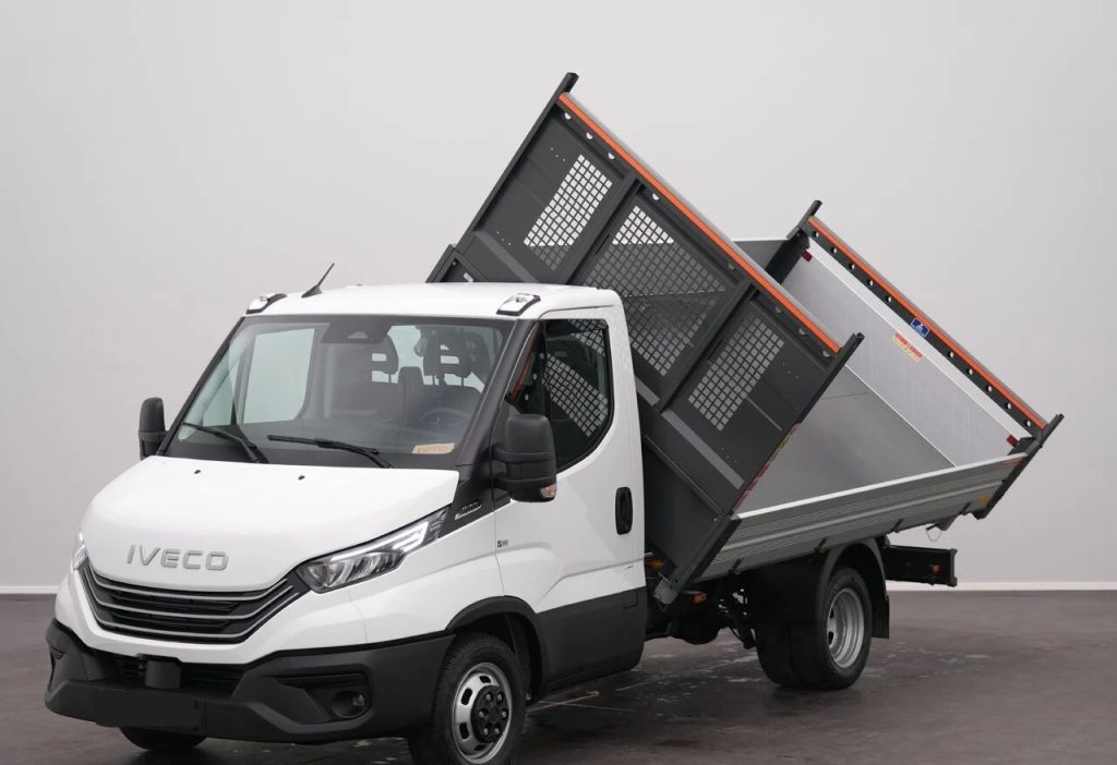 White Iveco tipper truck with its cargo bed raised for unloading, shown from the front-left in a studio setting