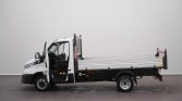 White flatbed truck with the cab door open, showing the driver's seat inside.