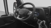Driver's cockpit view featuring a multi‑function steering wheel with built‑in controls, digital dashboard, and gear selector nearby.