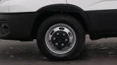 Close-up of a steel wheel and tire on a white commercial van side panel.