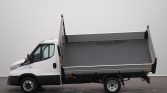 White cab-forward dump truck with a raised steel cargo bed, shown in side profile against a gray background, ready to dump.