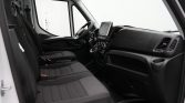 Front interior of a modern van: two black cloth seats, steering wheel, central touchscreen display, and dashboard controls visible.