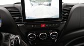 Car dashboard with a large touchscreen showing the rear-view camera in a garage setting