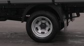 Close-up of a heavy-duty truck wheel: silver rim, black tire, with undercarriage and fender nearby.
