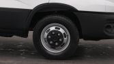 Close-up of a van's front wheel and tire, showing a silver steel wheel and black fender against a white body.