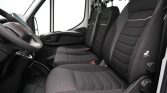 Interior of a white panel van showing the driver’s seat and two front passenger seats in black fabric.