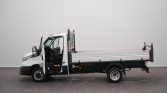 White flatbed truck with its driver door open in a plain indoor space.