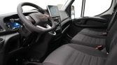 Interior view of a van cabin showing the steering wheel, digital dashboard, and two front seats with black fabric upholstery.