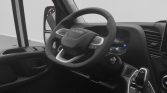 Interior of a modern vehicle showing the steering wheel, digital dashboard, and gear shifter from the driver's seat side, in grayscale.