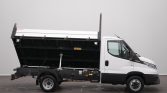 White dump truck with its bed raised in a loading position, displaying the hydraulic lift mechanism under the cargo area